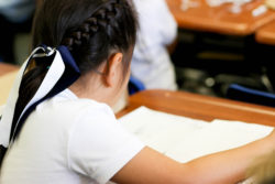 A student with a ribbon in her hair learns at a desk