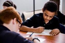 A student uses a pencil in a classroom